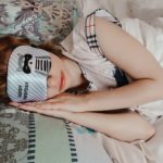 Frau schläft mit Augenklappe auf Matratze