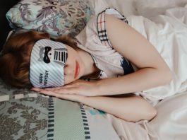 Frau schläft mit Augenklappe auf Matratze