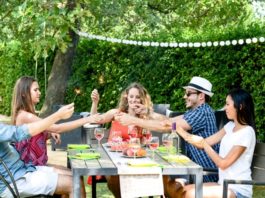 Freunde sitzen im Garten zusammen am Tisch