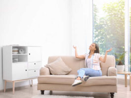 Frau sitzt im belüfteten Zimmer auf dem Sofa