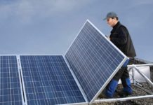 Mann montiert Solarmodul auf Flachdach