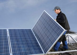 Mann montiert Solarmodul auf Flachdach