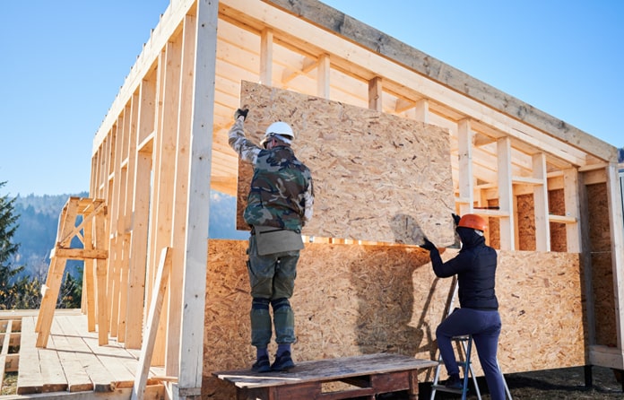 Arbeiter befestigen eine Wand am Holzrahmenhaus
